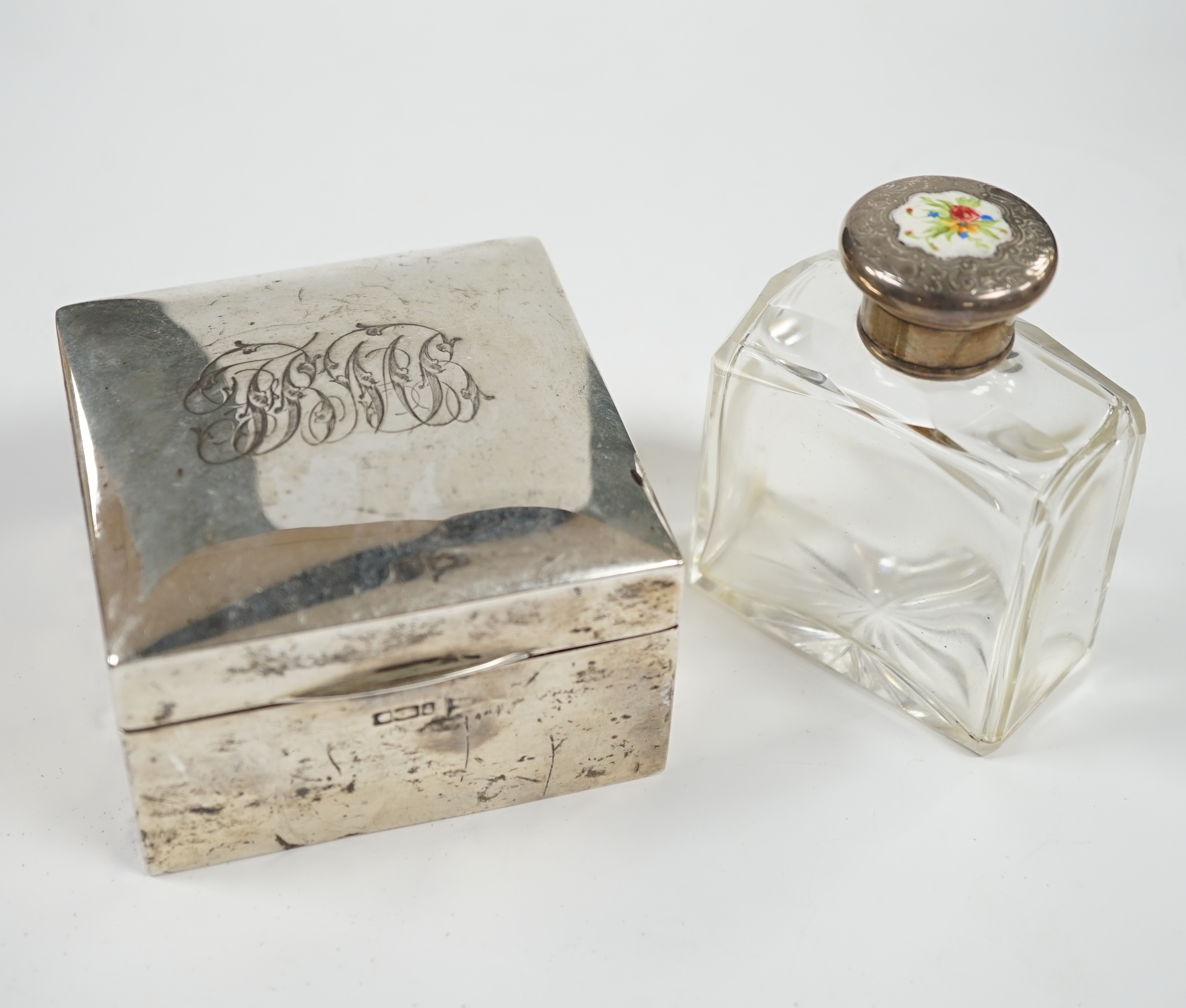 An Edwardian silver mounted cigarette box, marks rubbed, 90mm, together with a white metal and enamel topped glass scent bottle. Condition - poor